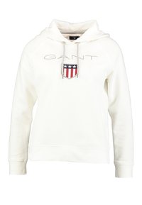 Sudadera blanca hecha de un tejido suave con capucha ajustable, que presenta un logotipo gris "GANT" y un parche con un escudo que incluye elementos en rojo, blanco y azul.