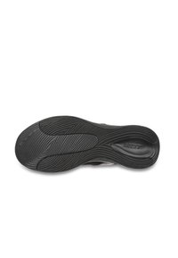 Suela de zapato de goma negra con un patrón en forma de ola, textura suave y un logotipo prominente. Forma curvada para un soporte ergonómico.