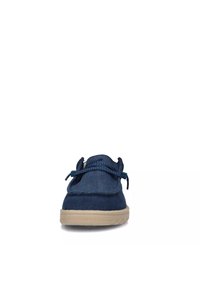 Scarpa slip-on in tela blu navy con punta rotonda, suola in gomma beige chiaro e lacci decorativi blu nella parte superiore. Texture liscia, design minimale.