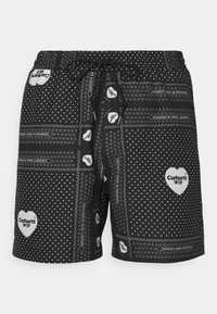 Bañadores negros de tejido ligero, con lunares blancos, logotipos de corazones y una cintura con cordón para un ajuste ajustable.