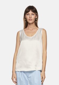 Satin sleeveless top in off-white with a scooped neckline and loose fit, featuring a smooth texture and subtle sheen.