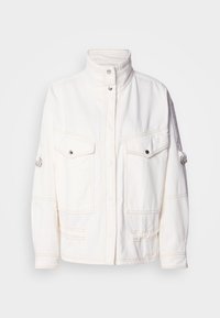 White denim jacket with a high collar, two front pockets, silver snap buttons, and contrasting stitching details. Features a relaxed fit.