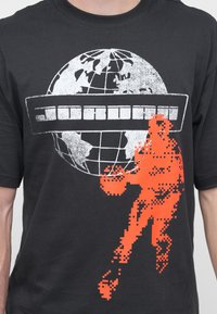 Μαύρο μπλουζάκι με άσπρο παγκόσμιο χάρτη, pixelated πορτοκαλί παίκτη μπάσκετ και οριζόντιο λευκό κείμενο σε μπλοκ πάνω στον παγκόσμιο χάρτη.