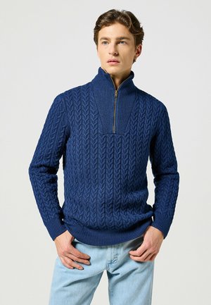 Granatowy sweter z dzianiny z pół-zamkiem i teksturowanym wzorem w warkocze. Długie rękawy oraz ściągacze przy rękawach i u dołu.