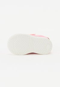Różowe tekstylne sneakersy z teksturowaną białą gumową podeszwą. Posiadają płaski obcas oraz zapięcie na rzep dla pewnego mocowania.