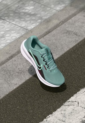 Sneaker de course Nike en mesh vert menthe, avec des accents noirs et bordeaux, semelle blanche, d'un dessus texturé et d'un intérieur rembourré.