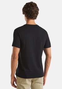 Svart kortärmad T-shirt i mjuk bomull, med en klassisk rund halsringning och en slät yta utan synliga mönster eller detaljer.