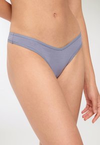 Tanga in cotone di un leggero viola, a vita bassa e con bordi senza cuciture, caratterizzato da una texture liscia e dettagli di cucitura minimi.