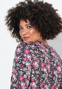 Blumenmusterkleid mit schwarzem Hintergrund, das mit rosa, weißen und grauen Blumen verziert ist. Weicher Stoff, lässige Passform und runder Ausschnitt.
