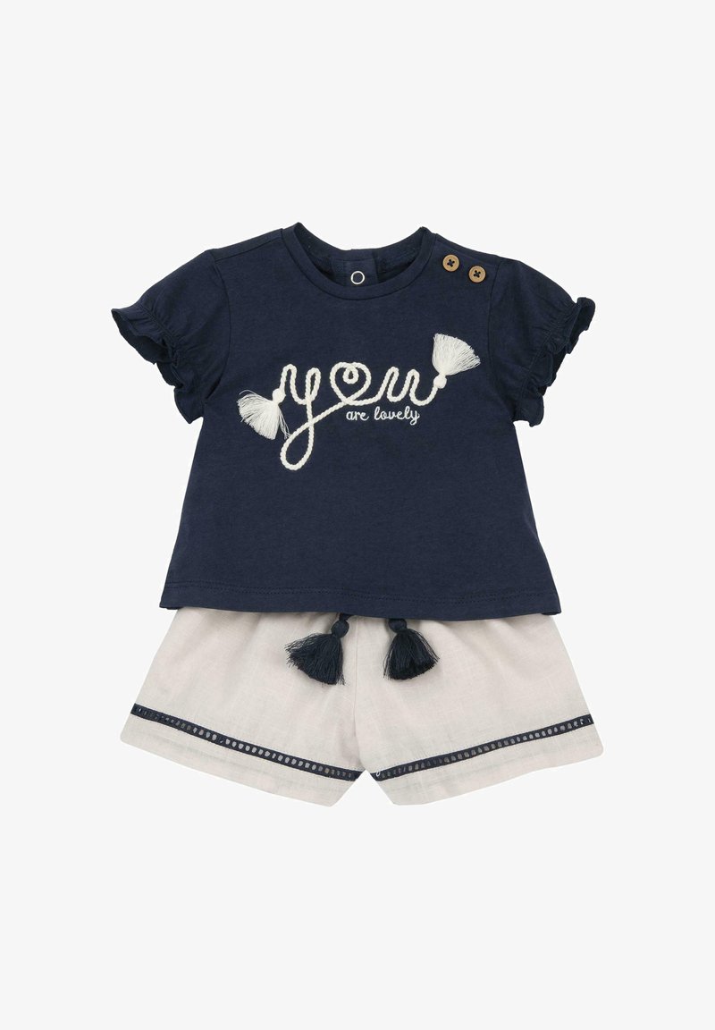 Haut bébé manches courtes bleu marine avec broderie « you are lovely » et pompons, associé à un short clair avec liseré bleu marine et pompons.