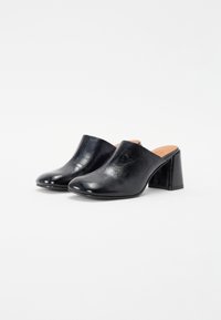 Mule in pelle nera con finitura liscia, punta arrotondata e tacco a blocco moderato. Il design presenta una parte posteriore aperta per una facile indossabilità.