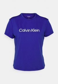 Camiseta de cuello redondo morada de manga corta, con el logo blanco de "Calvin Klein" en el pecho; tejido suave y diseño ajustado.