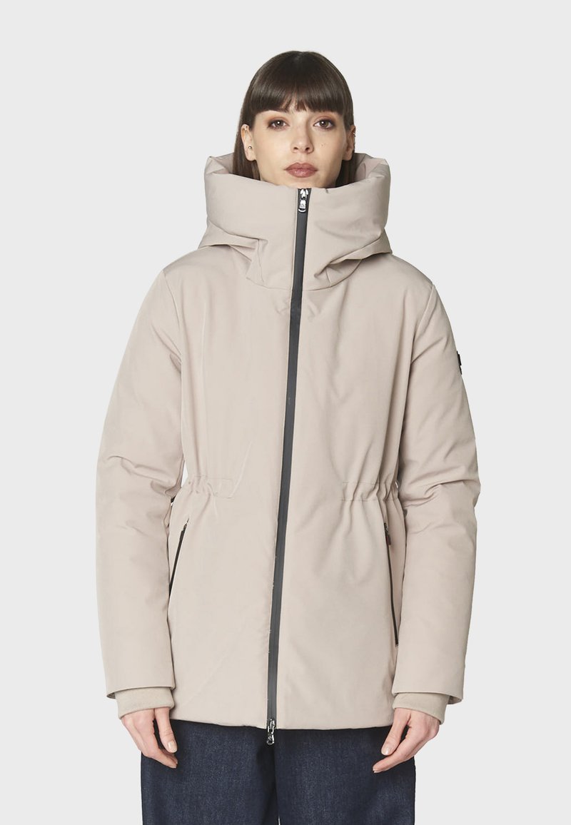 Chaqueta acolchada color beige claro con un cuello alto, cintura ceñida y cierre de cremallera. Presenta bolsillos laterales y puños de manga elásticos. Textura suave.