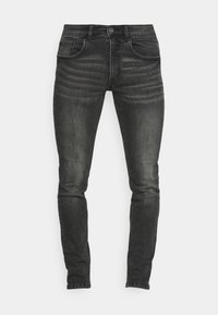 Jeans de denim negro ajustados con un lavado desgastado, cinco bolsillos y cierre de botón. Presentan un ligero efecto de desvanecimiento y detalles cosidos.