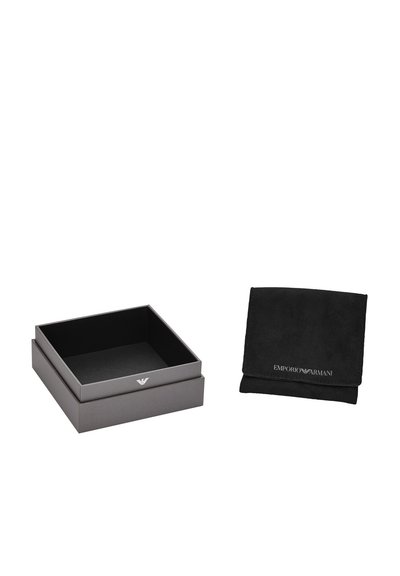 Šedá dárková krabice s logem, s matným povrchem. Vedle ní je černý semišový sáček s embosovaným textem. Oba mají minimalistický design.