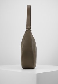 Borsa a spalla in pelle marrone con texture, dotata di una lunga tracolla. Presenta una forma affusolata e liscia, con un sottile dettaglio di cucitura lungo il lato.