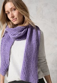 Écharpe violette côtelée en matériau doux, avec une texture subtile et une petite étiquette accrochée d'un côté. Portée enroulée autour du cou.