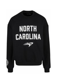 Svart hettegenser med kraftig hvit tekst "NORTH CAROLINA" og grafisk aksent. Ribbestrikkede mansjetter og kant, laget av mykt stoff.