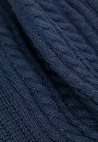 Tessuto lavorato a maglia di colore blu navy, che presenta un motivo a treccia e una texture morbida, con fibre visibili e un aspetto accogliente.