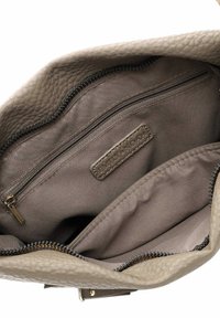 Beige læderhandtaske indvendigt med struktureret ydre stof. Har en lynlåslomme og glat foring, med et logo mærke på indersiden.