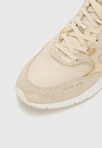 Sneaker beige con mesh testurizzato e finitura glitter. Presenta lacci piatti, punta arrotondata e suola in gomma bianca.