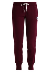 Bordeaux joggingbroek met een witte trekkoord, ribgebreide boorden en een ronde witte patch met een ster. Gemaakt van zachte stof voor comfort.
