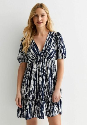Abito blu navy con motivo abstracto bianco, caratterizzato da scollatura a V profonda, maniche a palloncino e orlo a balze a strati. Realizzato in tessuto leggero.