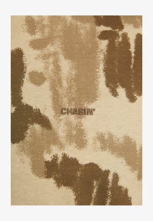 Tann- und braunfarbenes Stoff mit Camouflage-Muster, das den eingeprägten Markennamen "CHASIN'" in der Mitte zeigt. Glatte Textur, lässiges Design.