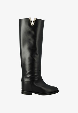 Bottes noires en cuir, montant jusqu'au genou, avec une texture lisse, un bout arrondi, une semelle plate et un accent métallique en V bien marqué en haut.