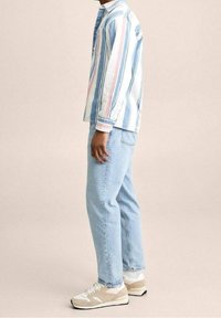 Pasiasty, długi rękaw, w pastelowych odcieniach niebieskiego, różowego i białego, w połączeniu z jasnoniebieskimi dżinsami i beżowymi trampkami z białymi akcentami.