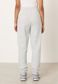 Svetlosivé tepláky vyrobené z mäkkej bavlnenej zmesi. Majú elastický pás a manžety, doplnené o sivé športové topánky.