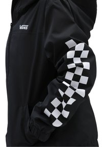 Black windbreaker with a white checkerboard pattern on the sleeve. Features a front zipper and elastic cuffs. Vans logo on the chest.