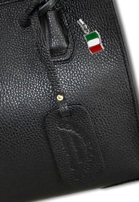 Zwarte leren handtas met een gestructureerd oppervlak, gouden hardware en een kleine metalen Italiaanse vlag charme eraan bevestigd.