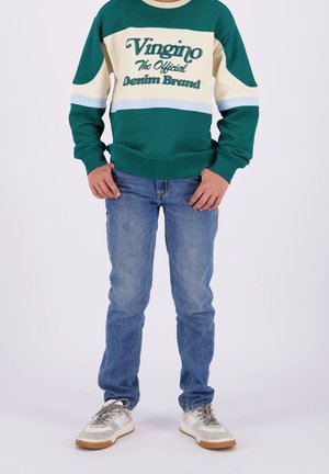 Sweatshirt vert et crème avec des accents bleus arborant le texte "Vingino", associé à un jean bleu clair et des baskets gris et blanc.