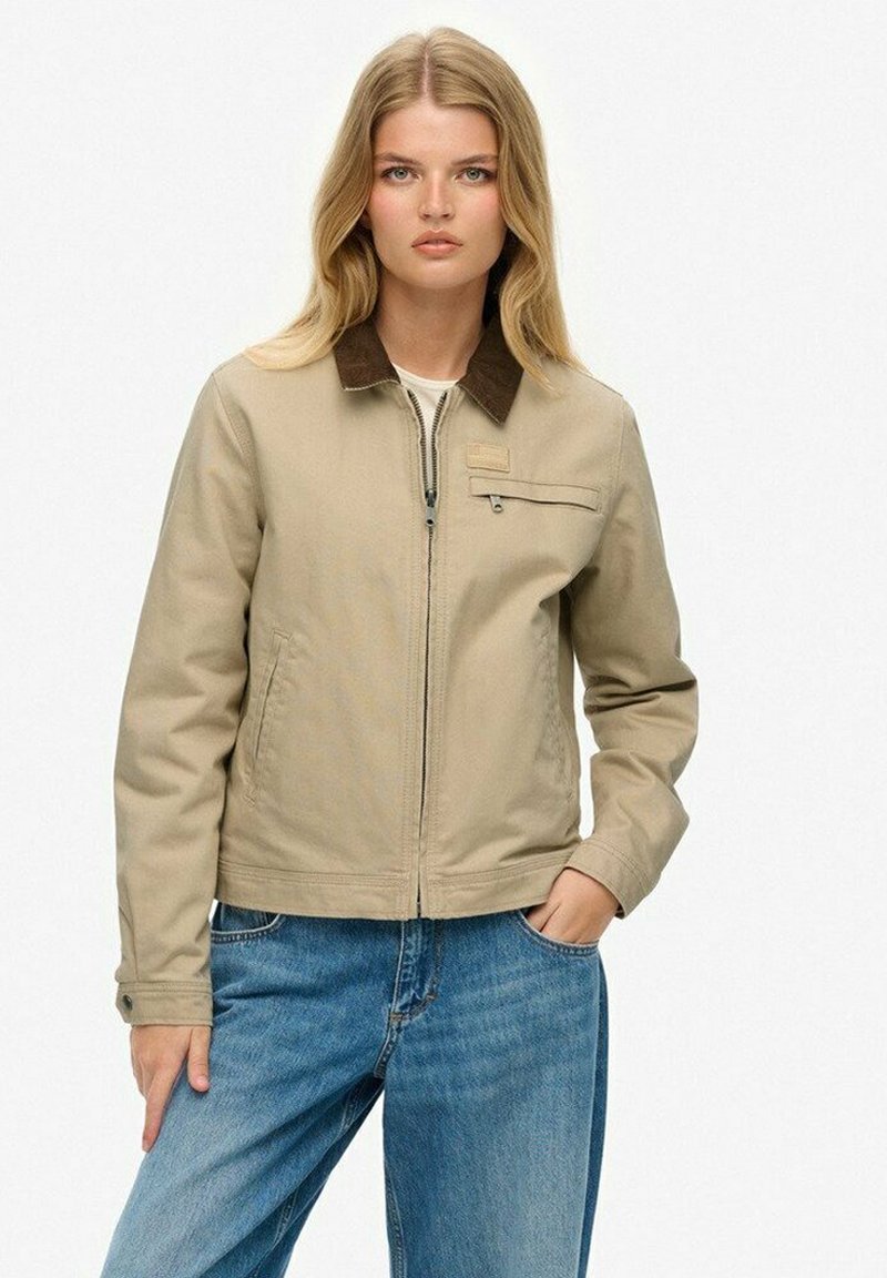 Veste en mélange de coton beige avec un col en velours côtelé marron, fermeture éclair sur le devant et poches latérales. Équipée d'une petite poche poitrine et d'une coupe décontractée.