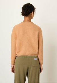 Peenevärvi kootud kampsun pehme tekstuuriga, ümar dekoltee ja pikad varrukad, kombineeritud oliivroheliste pükstega, millel on logopatch.