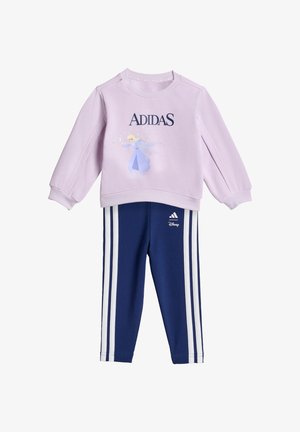 Felpa lilla con la scritta "ADIDAS" e un personaggio Disney stampato, abbinata a pantaloni blu navy con strisce laterali bianche e dettaglio logo.