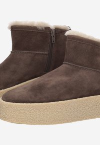 Bottes chelsea en daim marron avec une doublure en fausse fourrure crème douce. Présentent une fermeture éclair sur le côté et une semelle plateforme texturée de couleur beige clair.