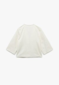 Witte katoenen top met driekwartmouwen, ronde halslijn en een losse pasvorm. Effen textuur zonder zichtbare patronen of accenten.