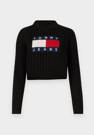 Svart ribbestrikket genser med V-hals, med et rektangulært Tommy Jeans-logo i blått, hvitt og rødt på forsiden.