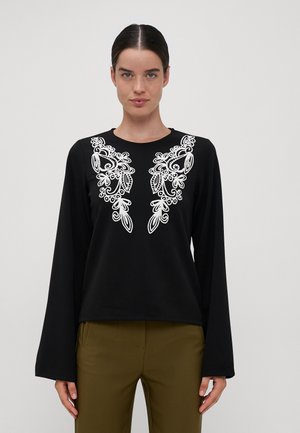 Black long-sleeve top featuring white floral embroidery on the chest, with a round neckline and a relaxed fit. Smooth fabric texture.