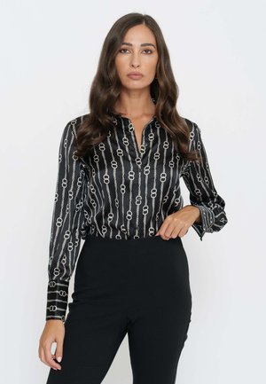 Blusa in satin nero con colletto, maniche lunghe e motivo a catena argentata. Il tessuto ha una finitura lucida e una vestibilità aderente.