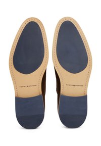 Semelle en daim marron avec une base en cuir beige lisse et une section en caoutchouc bleu foncé. Présente des coutures contrastantes et un détail de logo.