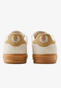 Zapatillas con parte superior de textil crema, lengüeta de piel en tono marrón claro y suela de goma. Presenta un logo de laurel bordado en la parte trasera.