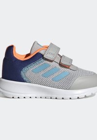 Šedá sportovní bota s síťovaným svrškem, modrými akcenty a dvojitými suchými zipy. Má pevnú námořnickou patu a bílou gumovou podrážku.