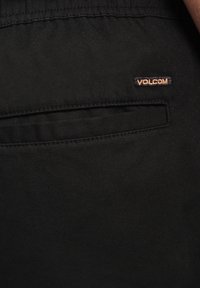 Zwarte stoffen shorts met een slank design en een enkele achterzak met een Volcom logo label. Het materiaal heeft een gladde textuur.