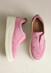 Różowe zamszowe buty wsuwane z grubą białą podeszwą, z przeszyciami i wyściełaną wkładką dla komfortu.