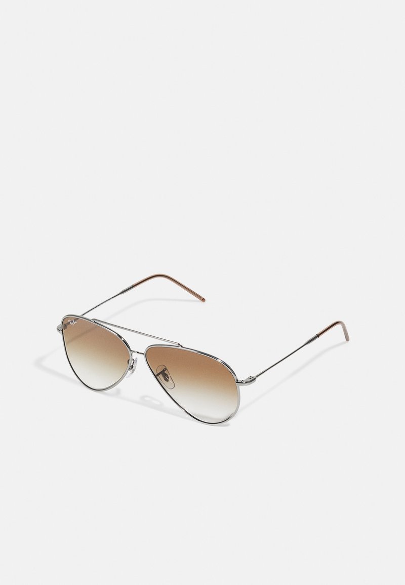 Óculos de sol aviador em metal com lentes castanhas degradê, armação fina em prata e hastes com detalhes castanhos. Design em forma de lágrima curvada notável.