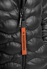 Schwarze Pufferjacke mit einem gesteppten Muster, ausgestattet mit einem orangen Reißverschluss-Zipper, der mit "MILESTONE" beschriftet ist, und einem schwarzen Reißverschluss.