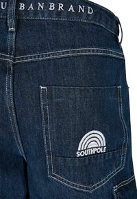 Mørkeblå denimshorts med en baglomme, der har et hvidt broderet Southpole-logo, kontrasterende syninger og et urban mærkebånd.